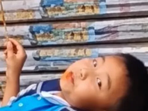 Mẹ đến đón muộn, cậu bé thản nhiên nằm trên bậc thềm ăn đồ ăn: Dân mạng bật cười vì quá chill!